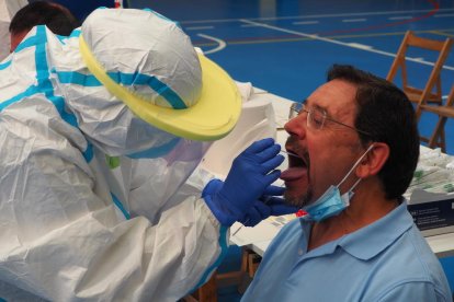 Plano detalle de un hombre haciéndose la PCR con un técnico sanitario en Sant Joan de les Abadesses.