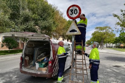 Unos operarios retiran una antigua señal ayer por la mañana.