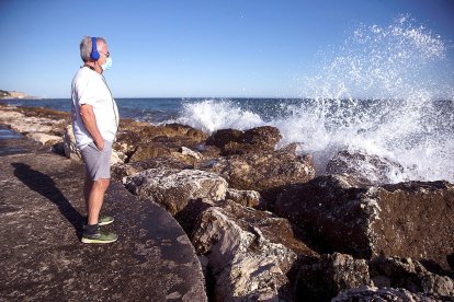 Un hombre escuchando música ante las olas del mar.