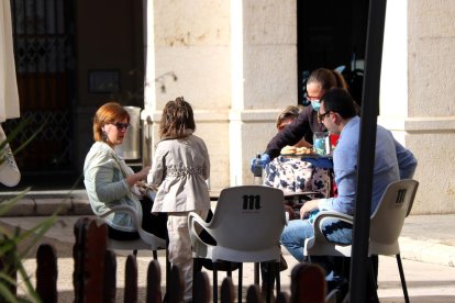 Una familia sentados en la terraza de un bar en Tortosa donde les sirven el desayuno.