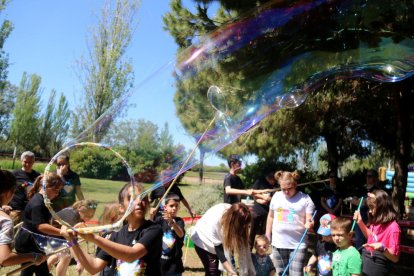 Plano general de varios niños jugando con pompas de jabón en la Festa Esplai.