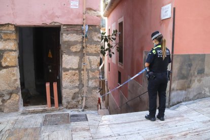 Una agent de la Guàrdia Urbana precintant l'entrada de l'edifici desallotjat dijous.