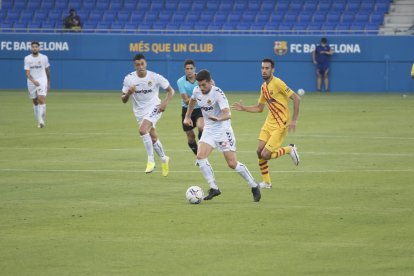 Javi Bonilla, perseguit per Sergio Busquets, a l'Estadi Johan Cruyff, aquest dissabte.