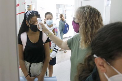 Una professora pren la temperatura a una alumna de secundària abans d'accedir a l'aula.