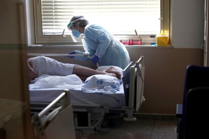 Una sanitaria atendiendo a un paciente en un hospital.