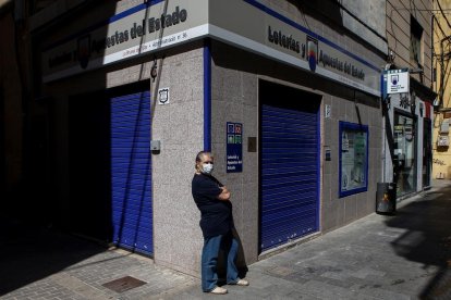 Un ciutadà transita enfront de l'edifici d'una administració de loteria al carrer de la Mar de Badalona (Barcelona)