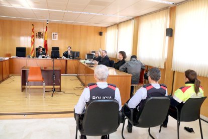 La sala de vistas de la Audiencia de Tarragona, con tres agentes de los Mossos en primer término, con el acusado sentado, de espaldas, a la derecha.