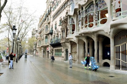 Unos turistas se fotografían delante de la Casa Batlló con mascarilla durante el primer día laborable del estado de alarma por el coronavirus.