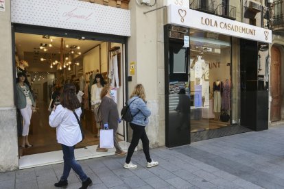 Persones andan|caminan con bolsas|bolsos por el centro de Reus.