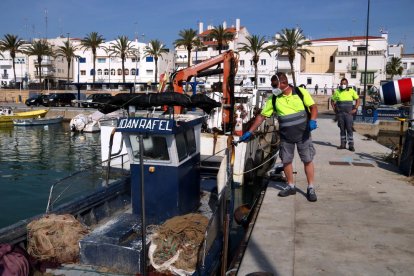 Un operari d'Alcanar desinfectant una de les embarcacions del port de les Cases d'Alcanar