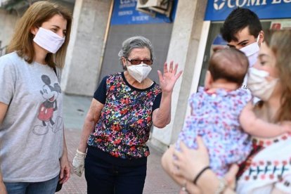 Un grup de persones amb mascaretes se saluden al carrer.