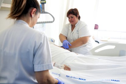 Dues infermeres, atenent una persona malalta ingressada en un hospital.