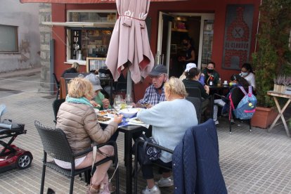 Pla obert on es veuen diverses persones a les taules d'una terrassa de bar