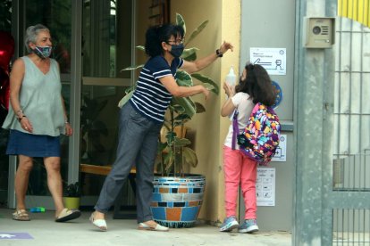 Una niña desinfectándose las manos con gel hidroalcohólico en la puerta de la escuela.