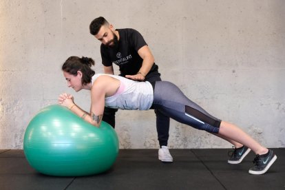 El director del gimnàs Essential Fit ajudant a una alumna a fer bé l'exercici en una imatge d'arxiu