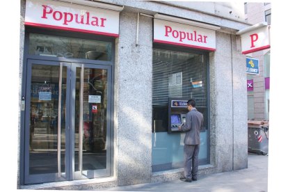 Imagen de archivo de un hombre treient dinero en el banco popular.