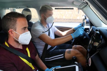 Un profesor de la autoescuela Hoy-voy Tarragona y un alumno, con guantes y mascarilla durante una clase práctica de coche.