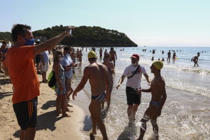 Uns nedadors són rebuts a l'arribada a la meta situada a la platja de la Móra.