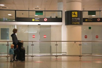 Una pasajera esperando delante la zona de llegadas en el aeropuerto de Barcelona.