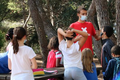 Un monitor de ocio haciendo una actividad con niños, todos con mascarillas.