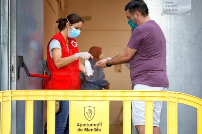 Una sanitaria poniendo hielo|gel a un usuario antes de un cribado por coronavirus en Manlleu.