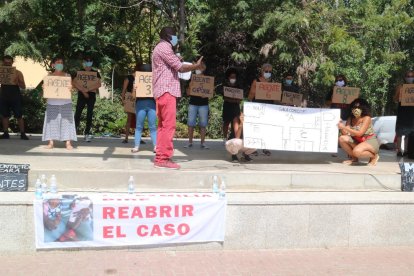 Ibrahima Sylla conduint una reproducció de l'operació policia al pis om vivia el seu germà, darrere un cartell que reclama la reobertura del cas de la mort del manter.