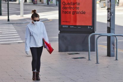 Una mujer con mascarilla caminando perl calle.