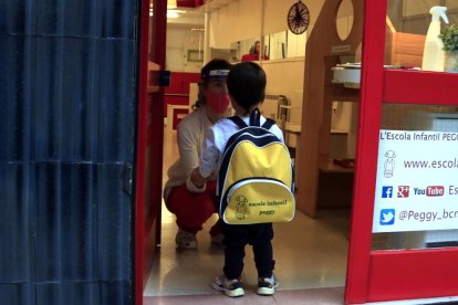 Un infant amb la mestra a l'entrada de l'escola infantil.