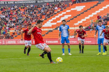 Javi Bonilla llença un penal contra el Lleida Esportiu amb Marc Trilles de fons.