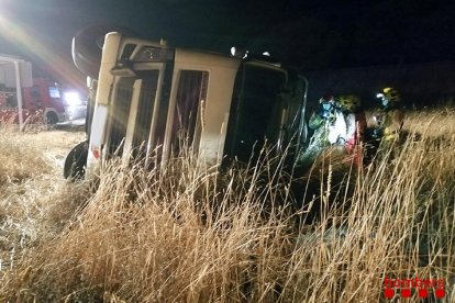 Els Bombers assistint el transportista que ha sortit de la calçada de l'AP-7 i ha acabat bolcant el camió la matinada