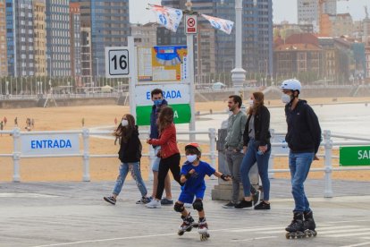 Un grup de persones passegen pel passeig marítim de la platja de Sant Lorenzo de Gijón