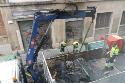 Operarios de limpieza retirando los contenedores quemados en la calle de la Selva del Camp.