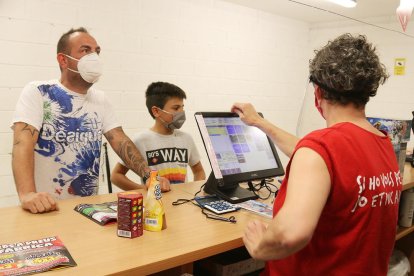 Una trabajadores de Petards CM atendiendo a dos clientes con mascarilla el día 15 de junio de 2020 en la tienda de Palau-solità.