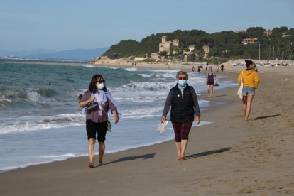 Dos mujeres con mascarilla andando por la playa de Altafulla en el primer día permitido para salir a practicar deporte.