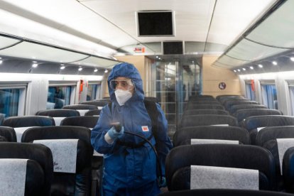 Plano abierto de un operario de una empresa de servicios desinfectando el interior de un tren de Renfe.