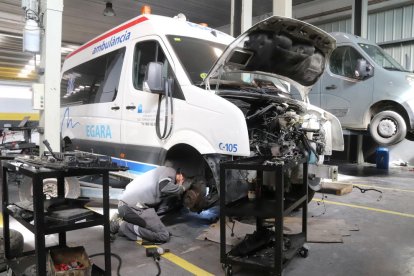 Pla mitjà d'un mecànic en un taller que només repara vehicles de serveis essencials