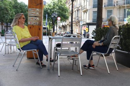 Plano abierto de dos personas hablando en una terraza de un horno en la Rambla de Catalunya en Barcelona.