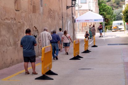 Una hilera de vecinos de Benifallet caminando hacia el Casal Municipal, donde se hace el cribado masivo por el brote de covid-19 en el municipio.