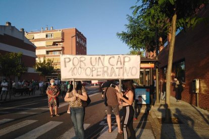 Dos personas sostienen una pancarta reivindicativa y, en el fondo, parte de la gente que se manifestó.