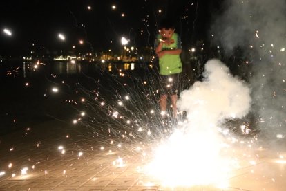 Un petardo explotando y un niño en segundo plano asustado en el paseo de Roses.