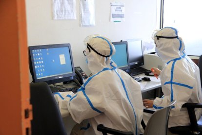 Dos médicos con el equipo de protección individual por el coronavirus consultando información de pacientes con covid-19 en el ordenador, en el Hospital del Mar.