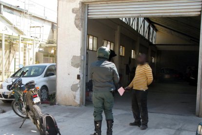 Pla general d'un agent de la Guàrdia Civil i d'un treballador del taller clandestí de Valls durant l'actuació policial en aquesta nau.