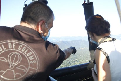 El pilot assenyala un punt del paisatge a una passatgera del vol aerostàtic a la Garrotxa