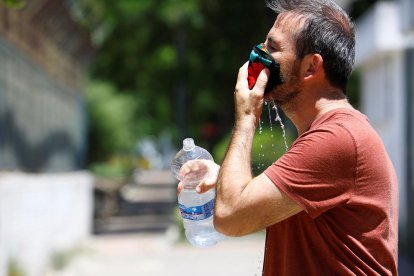 Un hombre remojando la mascarilla para afrontar las altas temperaturas.