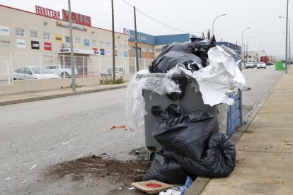 Contenedores llenos de basura y trastos en el polígono industrial de Valls, ante un negocio de una ferretería.