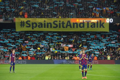 Cartell de Tsunami Democràtic amb el lema 'Spain, sit and talk!' a l'inici del clàssic al Camp Nou darrere dels jugadors.