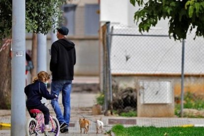 Una niña sale en bicicleta, el padre y el perro