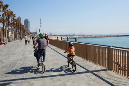 Una familia circula en bici por el paseo marítimo de Barcelona este domingo.