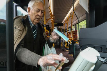 Un usuario, con la mascarilla en la mano, pasando la tarjeta.