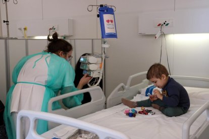 Una enfermera supervisa la medicación a un niño en el Hospital de Día de oncología pediátrica, donde se puede ver la caja de la medicación con una ilustración.